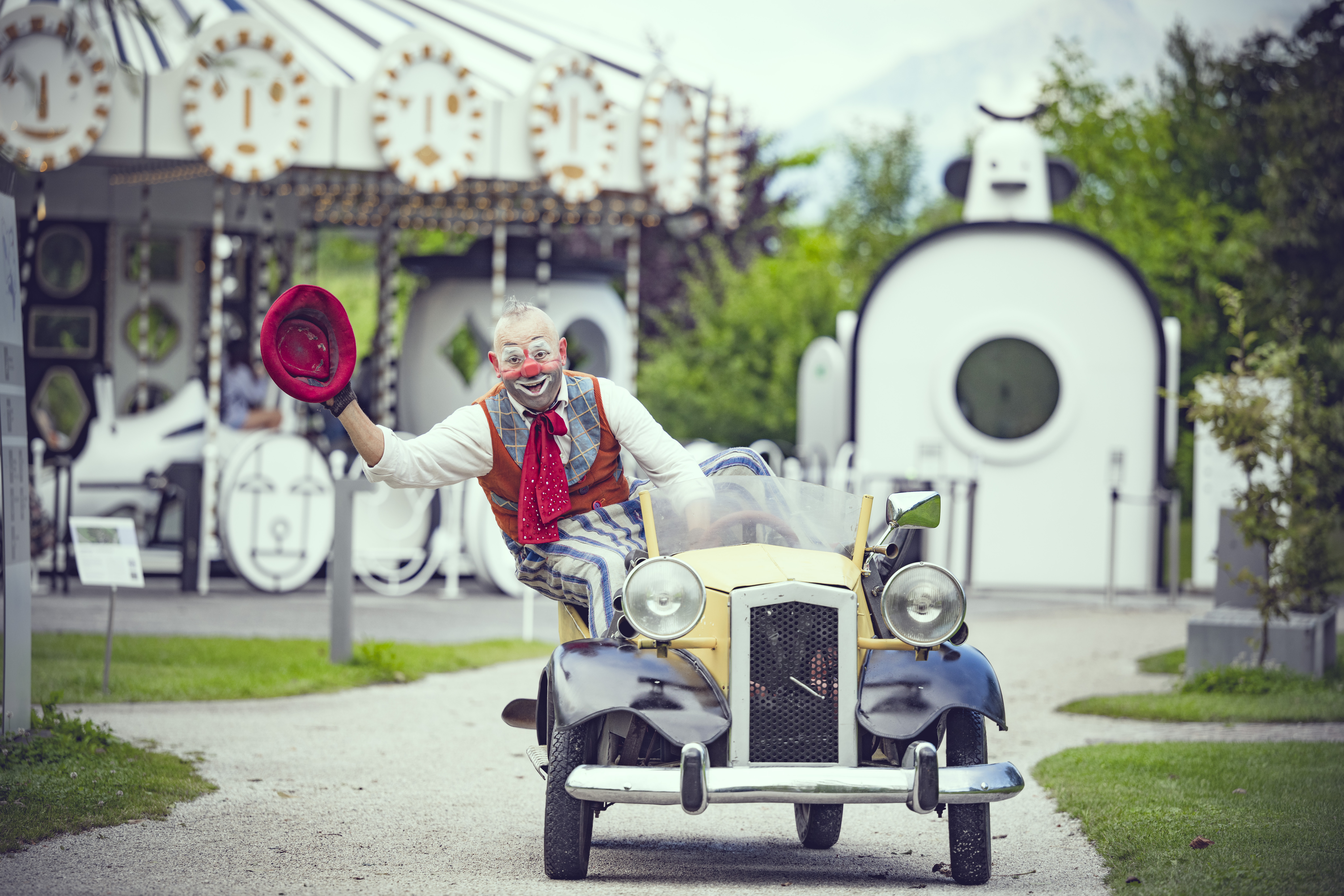 Clown Oriol tuckert mit seinem kleinen Auto durch den Garten der Swarovski Kristallwelten.